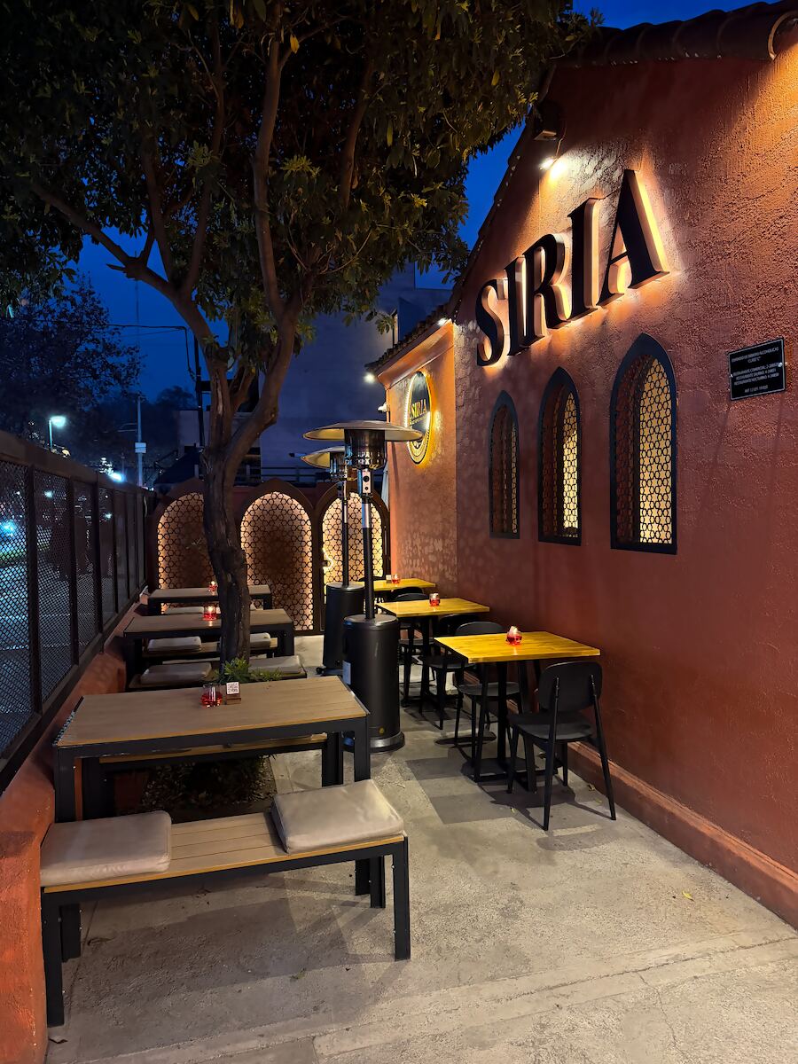 Terraza exterior al atardecer, con mesas frente a la fachada